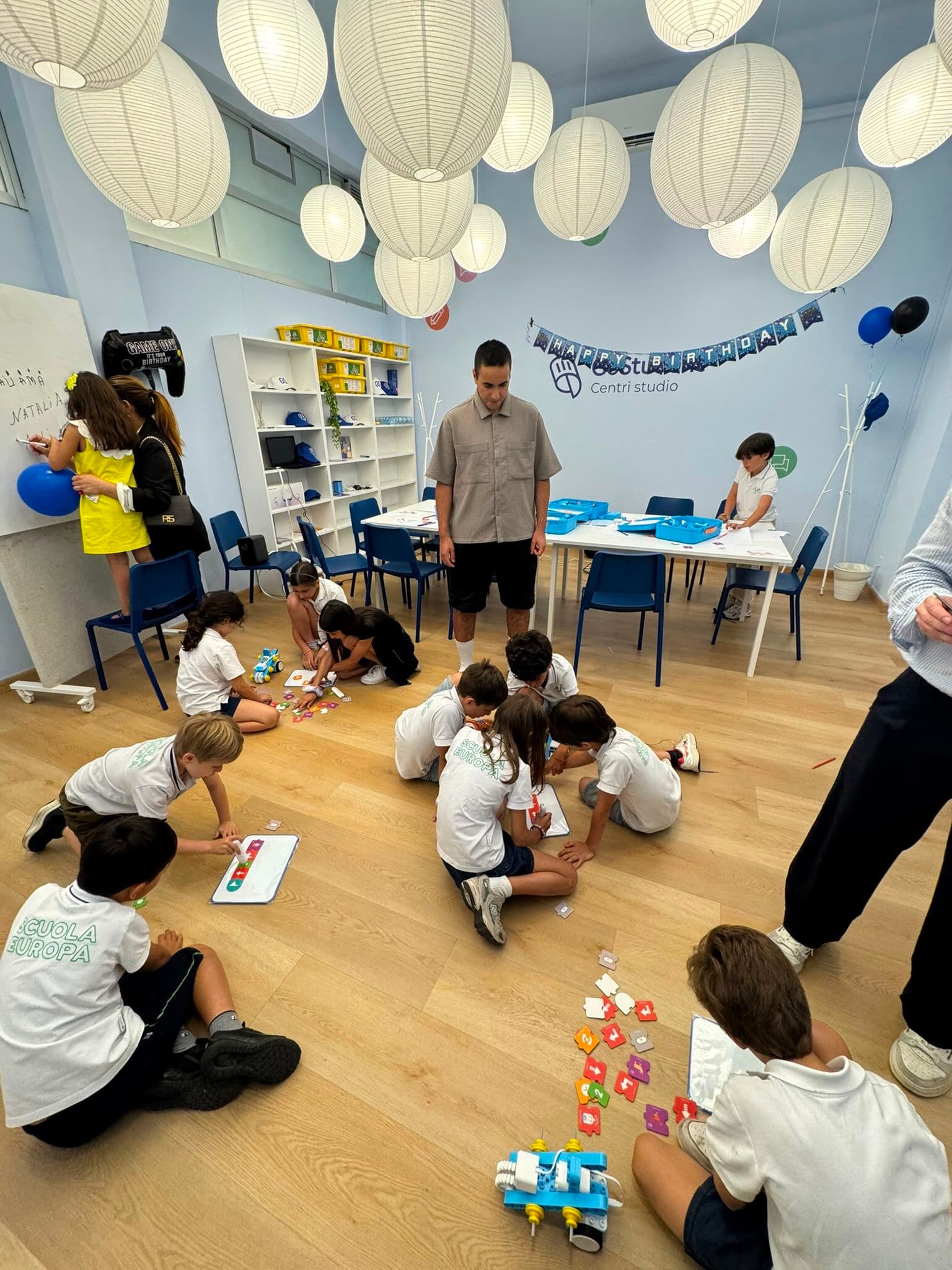 Niños construyendo robots LEGO en el suelo durante la fiesta